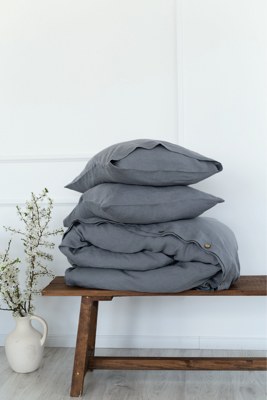 a stack of pillows sitting on top of a wooden bench